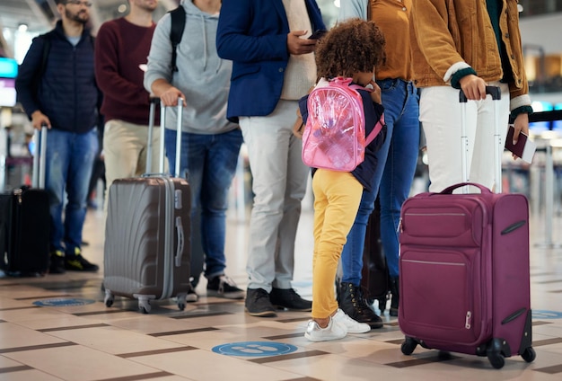 Viagem ao aeroporto e pernas de pessoas na fila para férias internacionais ou grupo de linha de imigração e espera com mala de bagagem e bolsa para viagem de avião de voo global e portão de check-in
