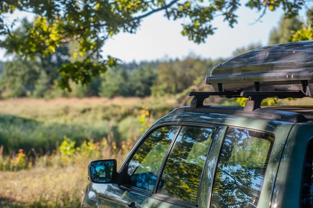 Viagem de caminhada de carro. um carro com um suporte para carros no teto fica em uma clareira na natureza sob um enorme carvalho no verão