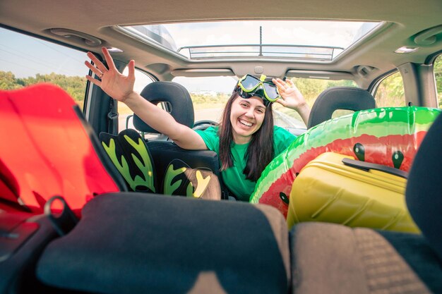 Viagem de carro de mar motorista de mulher sorridente no carro cheio de coisas de férias copie o espaço