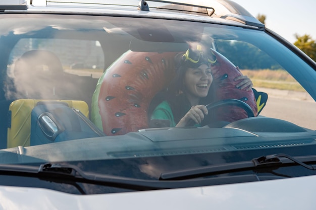 Viagem de carro de mar motorista de mulher sorridente no carro cheio de coisas de férias