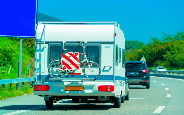 Viagem de férias com caravan car com bicicleta na estrada, suíça. campista e passeio de verão na estrada. viagem de férias em motorhome rv para recreação. passeio de movimento de minivan de motor home na natureza. cenário.