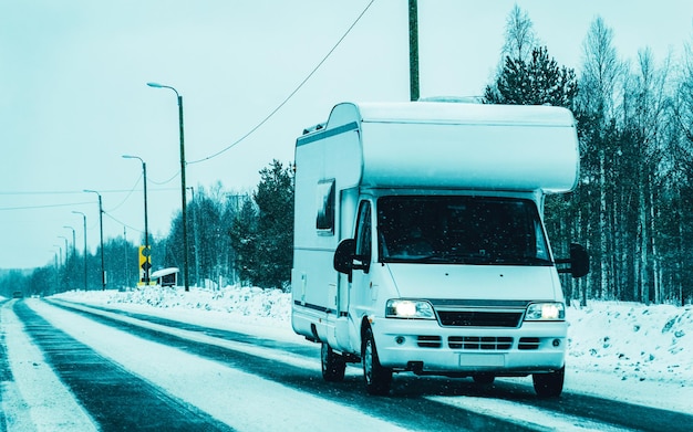 Foto viagem de férias com caravan car na estrada de neve de inverno da finlândia. campista e passeio de verão na estrada. viagem de férias em motorhome rv para recreação. passeio de movimento de minivan de motor home. veículo minivan.
