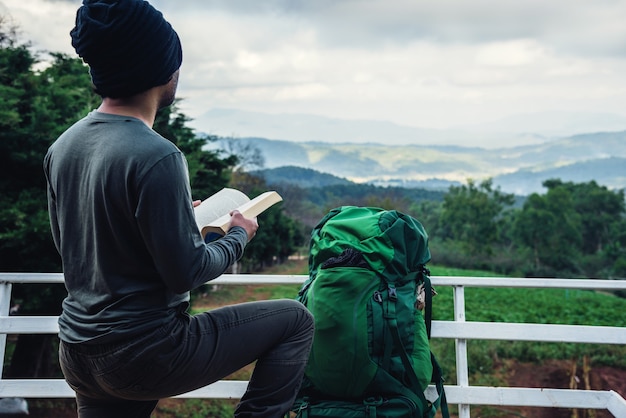 Viagem de homem asiático relaxar no feriado. os assentos relaxam, leia livros no ponto de vista da montanha. no doi inthanon chiangmai na Tailândia.