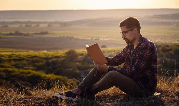 Viagem de homem relaxa nos assentos de férias relaxa lendo livros em penhascos rochosos