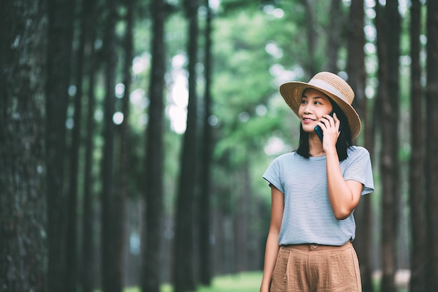 Viagem de inverno relaxa o conceito de férias. Jovem viajante feliz, mulher asiática com celular, visitando a floresta de pinheiros no Parque Suan Son bo Kaeo, Chiang Mai, Tailândia