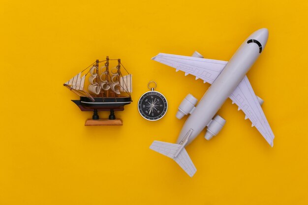 Viagem de minimalismo, aventura plana lay. Bússola e navio, avião de ar em fundo amarelo. Vista do topo