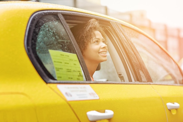 viagem de negócios, transporte e conceito de pessoas - jovem afro-americana sorridente dirigindo táxi na rua da cidade