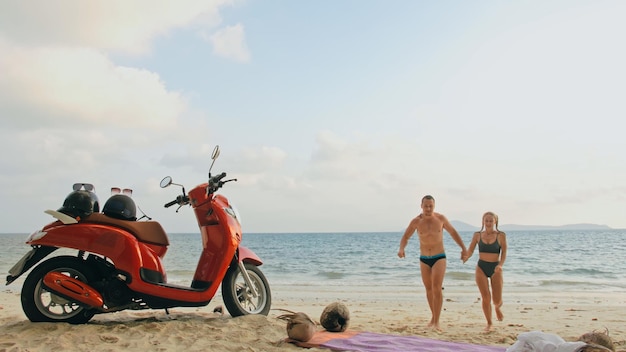 Viagem de scooter Lindo casal em moto vermelha em roupas brancas na praia de areia