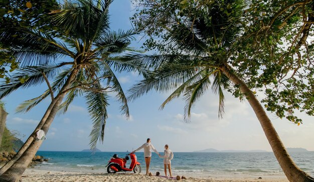 Viagem de scooter Lindo casal em moto vermelha em roupas brancas na praia de areia