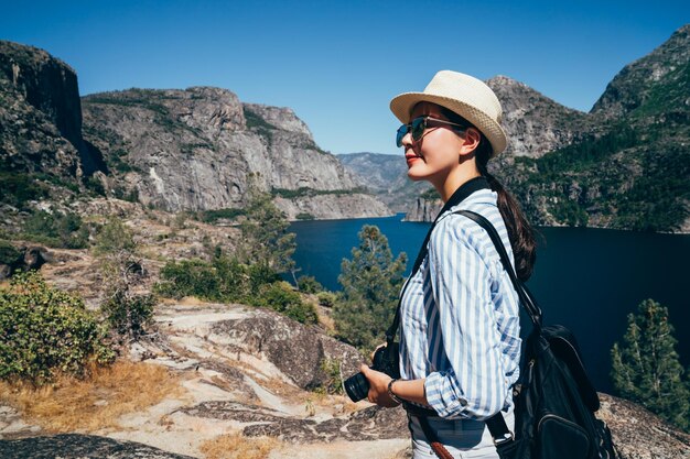 Viagem de turismo de senhora asiática no reservatório hetch hetch. jovem mochileiro vestindo chapéu de palha passeios bela vista da natureza da represa o shaughnessy. jovem mulher chinesa em pé ao ar livre ao redor da montanha