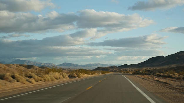 Viagem, dirigindo automóvel do Vale da Morte a Las Vegas, Nevada, EUA. Pegando carona viajando pela América. Viagem pela estrada, atmosfera dramática, montanha ao pôr do sol e deserto de Mojave. Vista do carro.