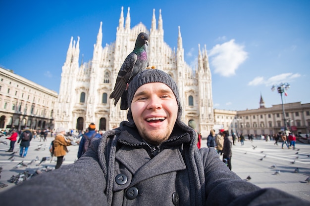 Viagem e excursão pela itália cara engraçado tirando selfie com pombos em frente ao duomo da catedral