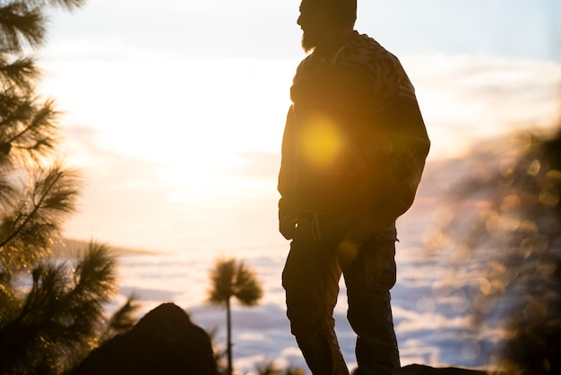 Viagem e vida selvagem natureza estilo de vida um homem em pé curtindo a liberdade e o incrível pôr do sol com o horizonte de montanhas e nuvens no fundo - luz solar de atividade selvagem de lazer ao ar livre