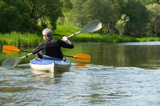 Viagem em caiaque em família para seigneur e senora Um casal idoso remando um barco no rio Uma caminhada na água Uma aventura de verão