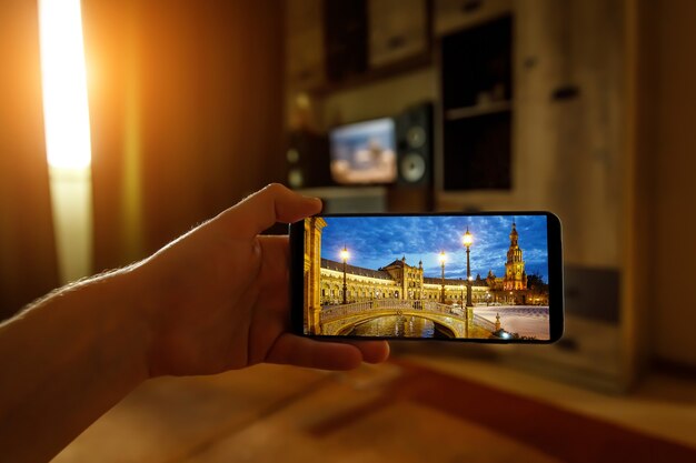 Viagem online para Sevilha, Espanha, de casa usando um telefone celular. Plaza de Espana na tela do smartphone
