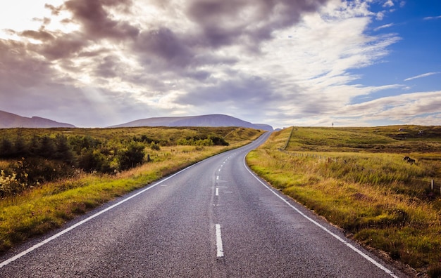 Viagem ou aventura estrada dramática abandonada no céu nublado da escócia