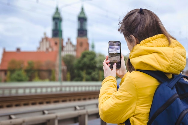 Viagem pela Europa Viagem à Polônia Poznan Menina turista tirando foto de igreja histórica no smartphone Trave