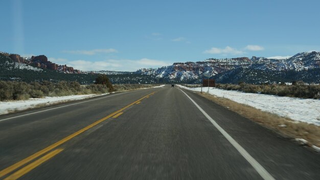 Viagem pelos EUA de Zion a Bryce Canyon, dirigindo um automóvel em Utah. Viajando de carona na América, Rota 89 para a floresta de Dixie. Viagem local de inverno, atmosfera calma e montanhas de neve. Vista do carro.