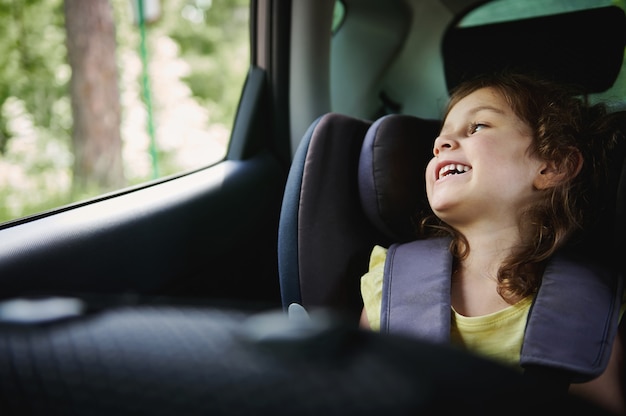 Viagem segura de carro com crianças presas na cadeirinha auto. Garota adorável no carro infantil saet