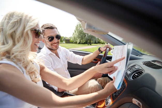 viagem, viagens, férias de verão e conceito de pessoas - homem e mulher felizes dirigindo em carro cabriolet com mapa