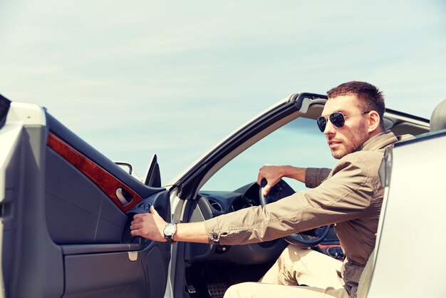 viagem, viagens, transporte, lazer e conceito de pessoas - homem feliz abrindo a porta do carro cabriolet ao ar livre