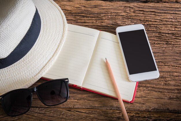 viagens, férias de verão, turismo e objetos conceito. close-up do chapéu, caderno, lápis, smartphone
