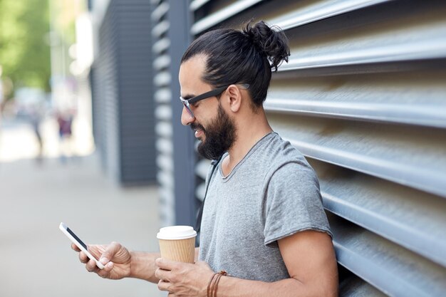 viagens, turismo, comunicação, tecnologia e conceito de pessoas - homem com mochila e xícara de café mensagens de texto em smartphone na rua da cidade