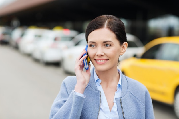 viagens, viagem de negócios, pessoas e conceito de turismo - jovem sorridente ligando e falando no smartphone sobre a estação de táxi ou a rua da cidade