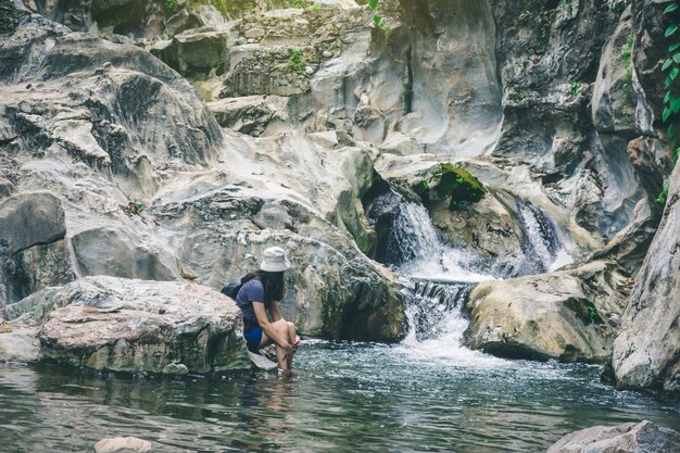 Viaja mujer sentada y disfruta del momento en la roca en la cascada en el parque natural