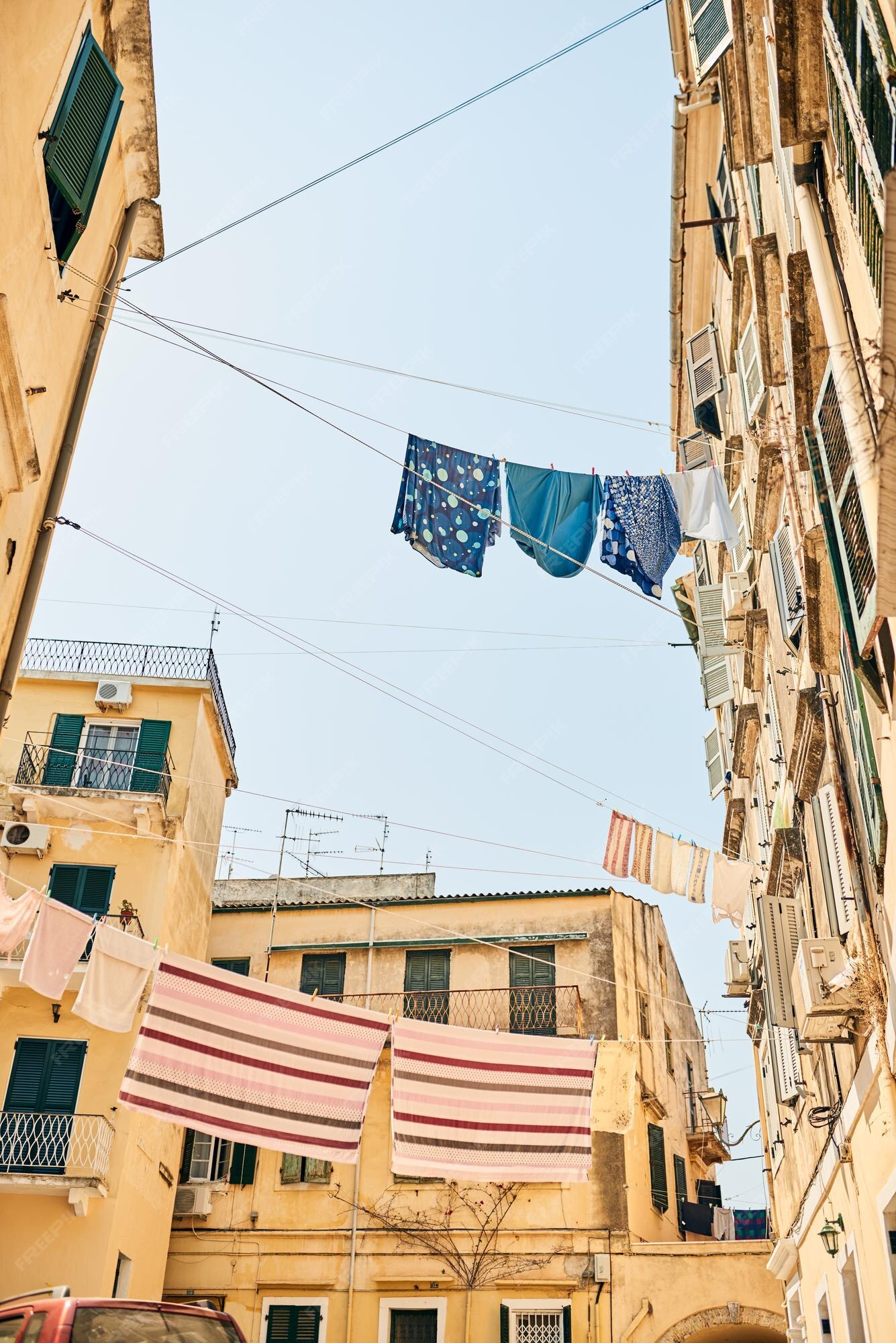 Viaja por el mundo y verás que las cosas se de manera diferente fotografía en ángulo bajo de ropa colgada de tendederos entre en una ciudad extranjera | Foto Premium