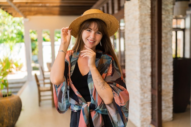 Viajando brunete mujer con sombrero de paja y elegante traje de verano enjong tropical vacatons en moderno resort