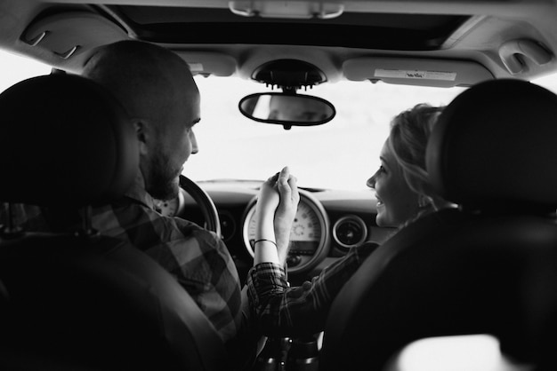 Viajando en coche de una joven pareja de un chico y una chica con camisas a cuadros