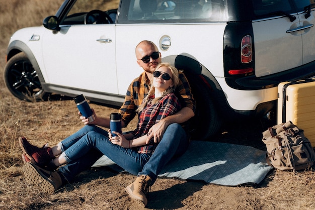 Viajando en coche de una joven pareja de un chico y una chica con camisas a cuadros