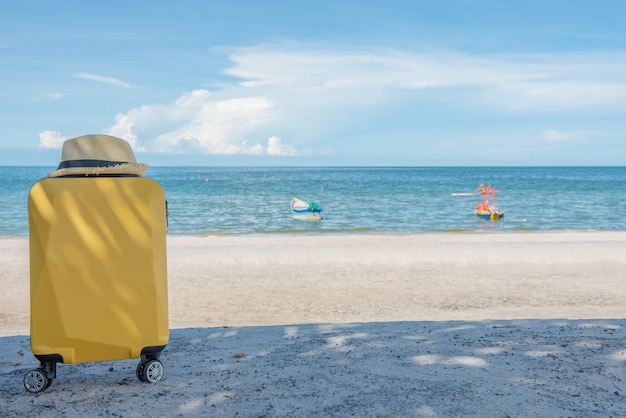 Viajando mala com chapéu na praia