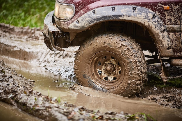 Viajando offroad em um caminhão offroad sujo Closeup de uma roda em uma poça e lama