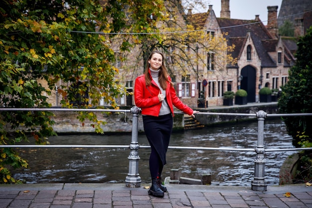 Viajando pela velha Europa Linda mulher como turista em Bruges, Bélgica, com jaqueta vermelha no outono