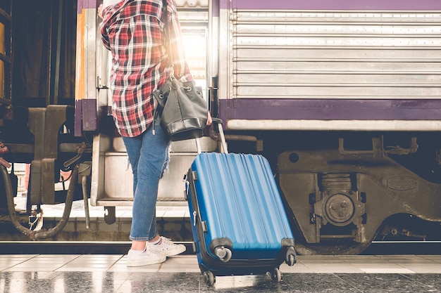 Viajando sozinho com malas esperando seu trem na plataforma da estação ferroviária no verão. Conceito de viagem sozinho.