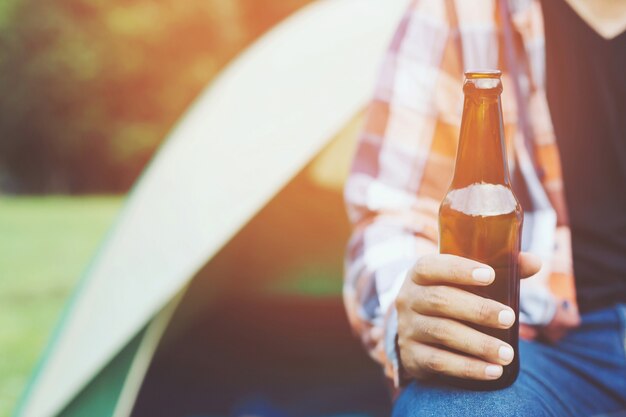 Viajando três jovens amigos se divertindo juntos Relaxe no acampamento de caminhada e bebendo cerveja em garrafas de Cheers e curtindo. Acampamento de férias Conceito de aventura de viagens.