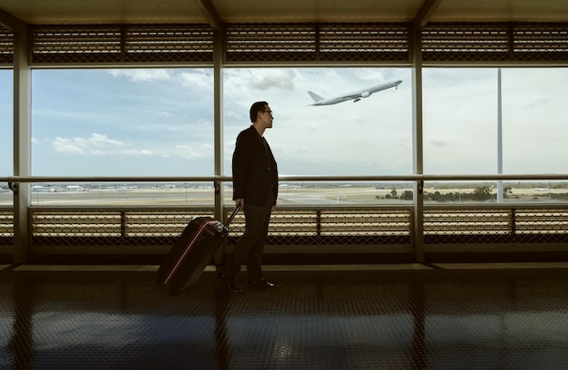 Viajando xAman y equipaje caminando en la terminal del aeropuerto y avión volando afuera