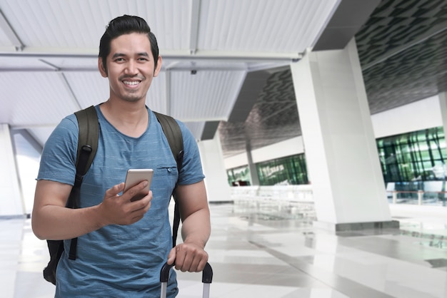 Viajante asiático alegre com mochila usando celular