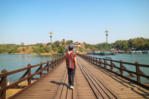 Viajante caminhando na Ponte Mon no rio Songkalia, no distrito de Sangkhlaburi, Kanchanaburi, Tailândia