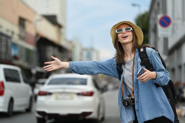 Viajante caucasiana levantando a mão chamando táxi na movimentada rua da cidade Conceito de turismo e transporte