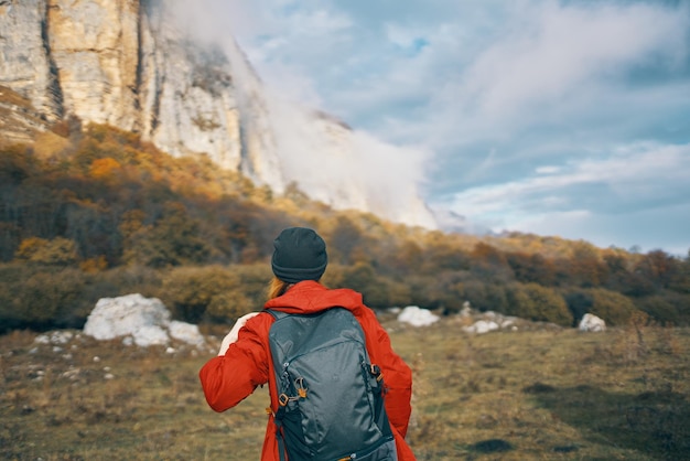 Viajante com mochila no outono nas montanhas céu azul nuvens rochas altas paisagem