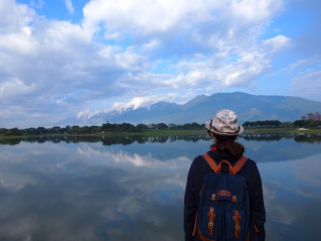 Viajante com mochila olhando o lago ao redor das montanhas