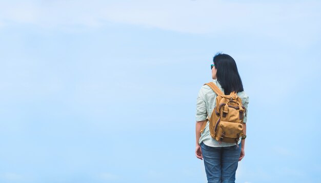 Viajante com mochila olhando para o céu azul, asia mochileiro mulher