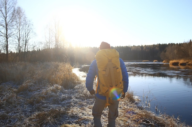 viajante com uma mochila à beira do rio / turista em uma caminhada ao norte, viagem de inverno