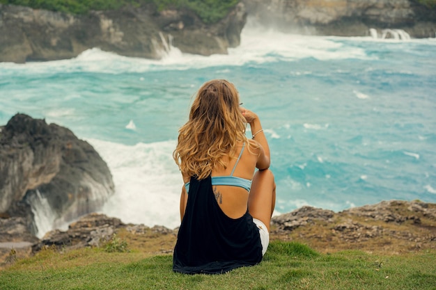 Viajante de fotógrafo jovem com uma câmera na beira de um penhasco tira fotos da natureza