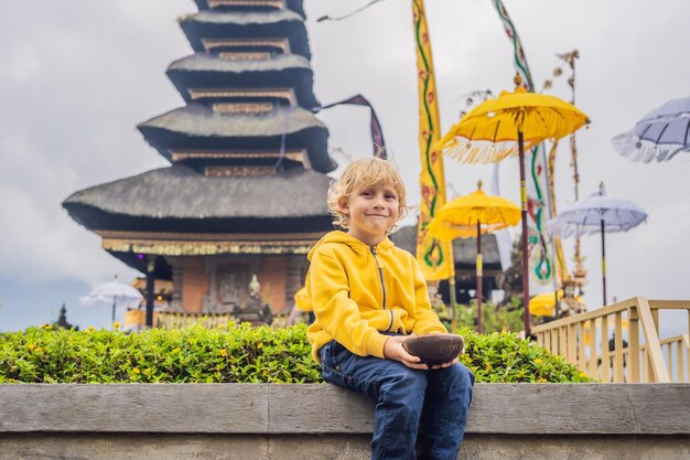 Viajante de menino no fundo de pura ulun danu bratan, bali. templo hindu cercado por flores no lago bratan, bali. grande templo de água shivaite em bali, indonésia. templo hindu. viajar com chi