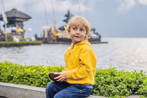 Viajante de menino no fundo de Pura Ulun Danu Bratan, Bali. Templo hindu cercado por flores no lago Bratan, Bali. Grande templo de água Shivaite em Bali, Indonésia. templo hindu. Viajar com chi