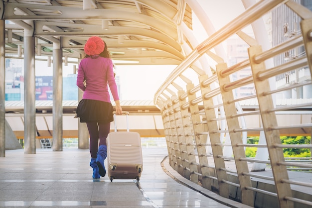 Viajante de mulher andando na passarela do aeroporto com a mala de viagem.